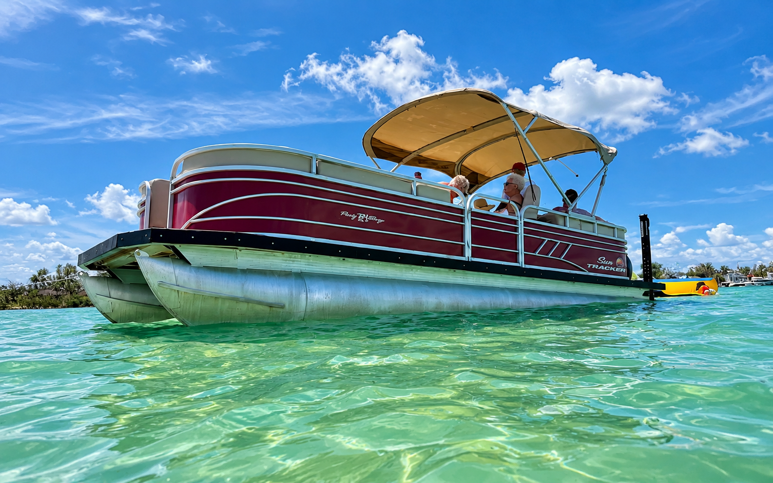 Squid Game, a burgundy Sun Tracker pontoon boat on clear Florida water